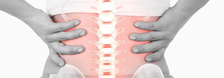 Close-up of a lower back with hands on both sides and an illuminated spine graphic over a red highlighted area.